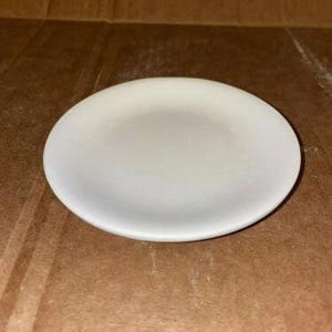 May include: A white ceramic saucer, ideal for displaying small items or serving snacks.
