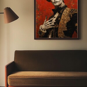 May include: A framed portrait depicting a person in Day of the Dead makeup and attire. The person wears a black jacket with gold detailing, a floral headpiece, and skull face paint. The background is red with floral patterns. The portrait hangs above a green sofa.