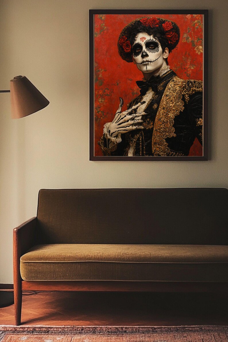May include: A framed portrait depicting a person in Day of the Dead makeup and attire. The person wears a black jacket with gold detailing, a floral headpiece, and skull face paint. The background is red with floral patterns. The portrait hangs above a green sofa.