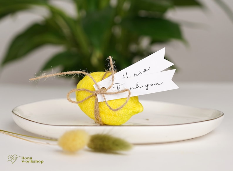 May include: A small yellow felt lemon tied with twine and a white tag that says "M. ria Thank you".