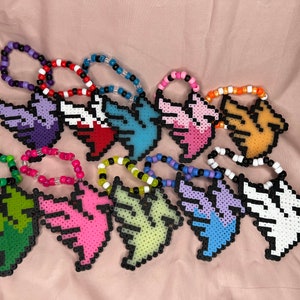 May include: A collection of colorful beaded bracelets with a pixelated bird design. The bracelets are made with various colors of beads, including purple, red, blue, pink, green, yellow, and white.