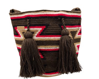 Puede incluir: Bolso de hombro tejido con un patrón geométrico en colores marrón, rojo y crema. El bolso tiene dos borlas marrones oscuras y la palabra "WANAAN" es visible. El bolso está hecho de un material grueso y duradero.