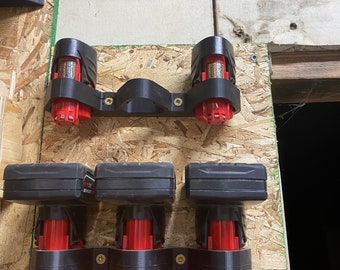 May include: A wall-mounted battery storage system for power tools. The system features black plastic holders with red and black battery packs. There is also a red and black tool bit holder with a variety of bits.