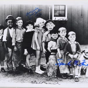 May include: A vintage black and white photograph featuring a group of children, some in hats, alongside a dog. The image includes signatures and the words "Best Wishes" and "Hal Roach".