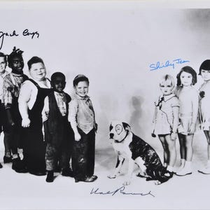 May include: A monochrome photograph of a group of children and a dog. The children are wearing vintage attire. The image includes the signatures "Jack Boys", "Shirley Jean", and "Hal Roach".