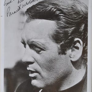 May include: Black and white photograph of a man in profile. The image is a close-up of the man's face, showing his nose, mouth, and ear. The photograph is signed with the words "Good luck Warren, Parnett McCoole".