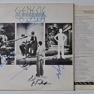 May include: Genesis album cover for "The Lamb Lies Down on Broadway" featuring black and white photos and signatures. The cover includes images of figures in various scenes, with the band's name and album title at the top.