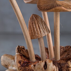May include: A wooden sculpture of mushrooms with detailed carvings. The mushrooms are arranged in a cluster on a wooden base.