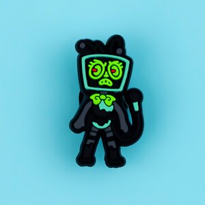 May include: A black and neon green shoe charm featuring a character with a television screen for a head. The character has a bow tie, a long tail, and a grumpy facial expression with red eyes, rendered in a flat, cartoon-style graphic design.