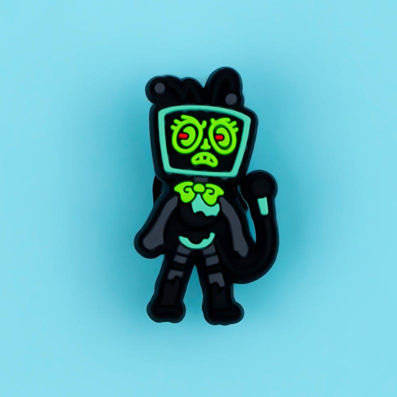 May include: A black and neon green shoe charm featuring a character with a television screen for a head. The character has a bow tie, a long tail, and a grumpy facial expression with red eyes, rendered in a flat, cartoon-style graphic design.