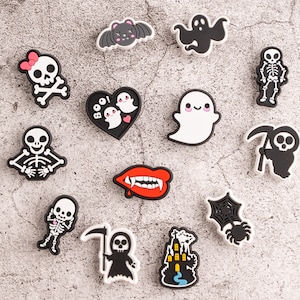 May include: A set of 12 Halloween-themed shoe charms featuring various spooky characters and symbols, including ghosts, skeletons, bats, a heart with the word "BOO!" and a spider web.
