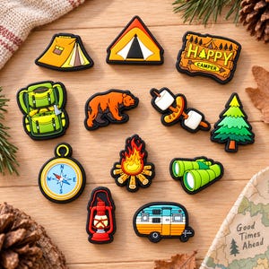 May include: A collection of twelve camping-themed shoe charms featuring a yellow tent, a triangular tent, a sign reading Happy Camper, a green backpack, an orange bear, a hot dog with marshmallows, a pine tree, a compass, a campfire, green binoculars, a red lantern, and a camper trailer.