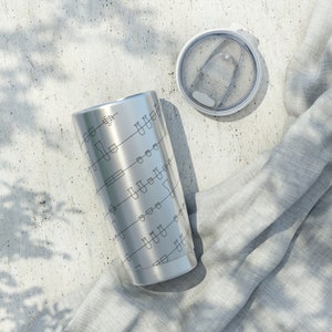 May include: A stainless steel tumbler with a black and white design of musical notes. The tumbler has a lid with a clear plastic top.