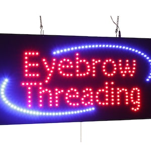 以下が含まれることがあります： 白い光で「Eyebrow Threading」と書かれた赤いLED看板。看板は黒色の背景で、青いLEDの縁取りがされている。