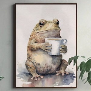Puede incluir: Pintura a la acuarela de una rana sosteniendo una taza de café blanca. La rana es de color marrón claro con manchas más oscuras y una expresión de mal humor. La taza contiene un líquido marrón claro. La obra de arte está enmarcada en un marco marrón oscuro.