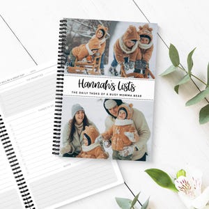 May include: A wire-bound notebook with a cover showing family photos in a snowy scene. The cover reads "Hannah's Lists: The Daily Tasks of a Busy Momma Bear." The open notebook displays lined pages for notes and lists.