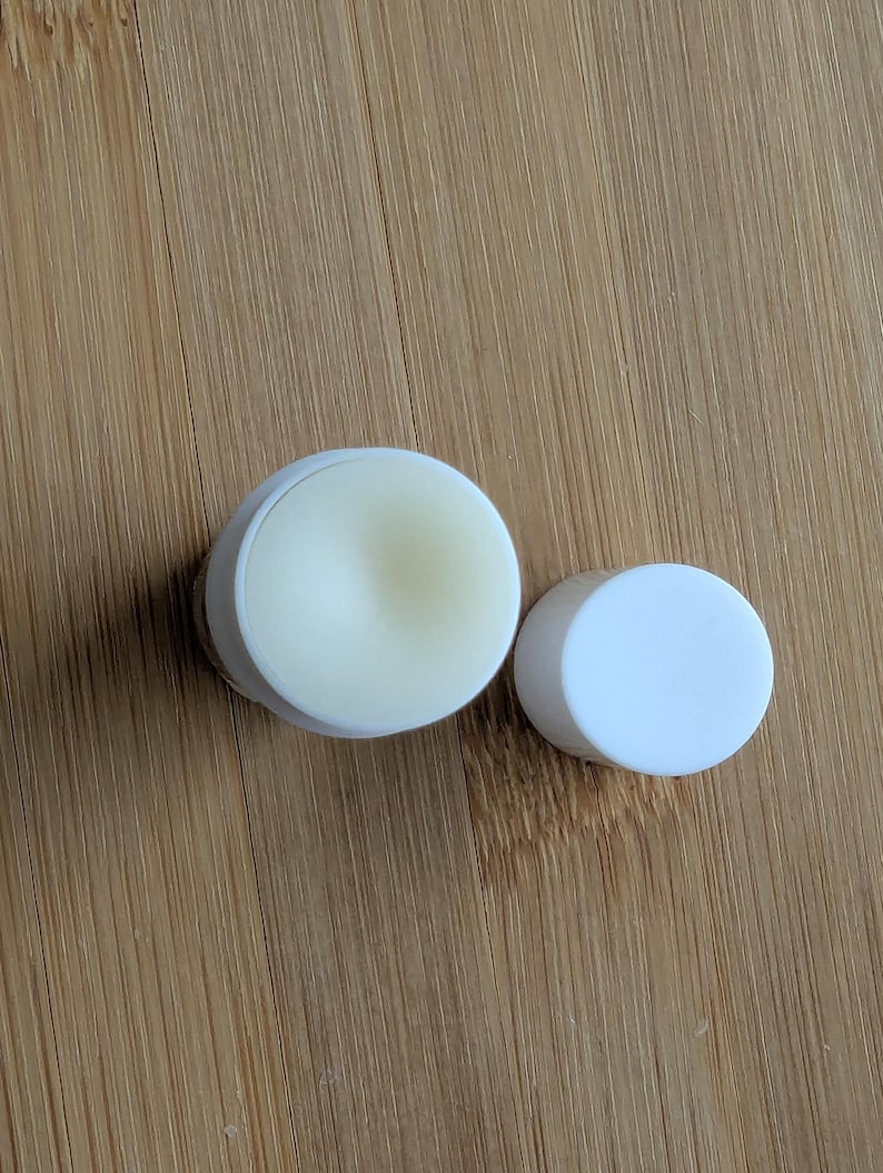 Puede incluir: Dos recipientes redondos blancos, uno con tapa y otro con una sustancia blanca y cremosa en su interior.