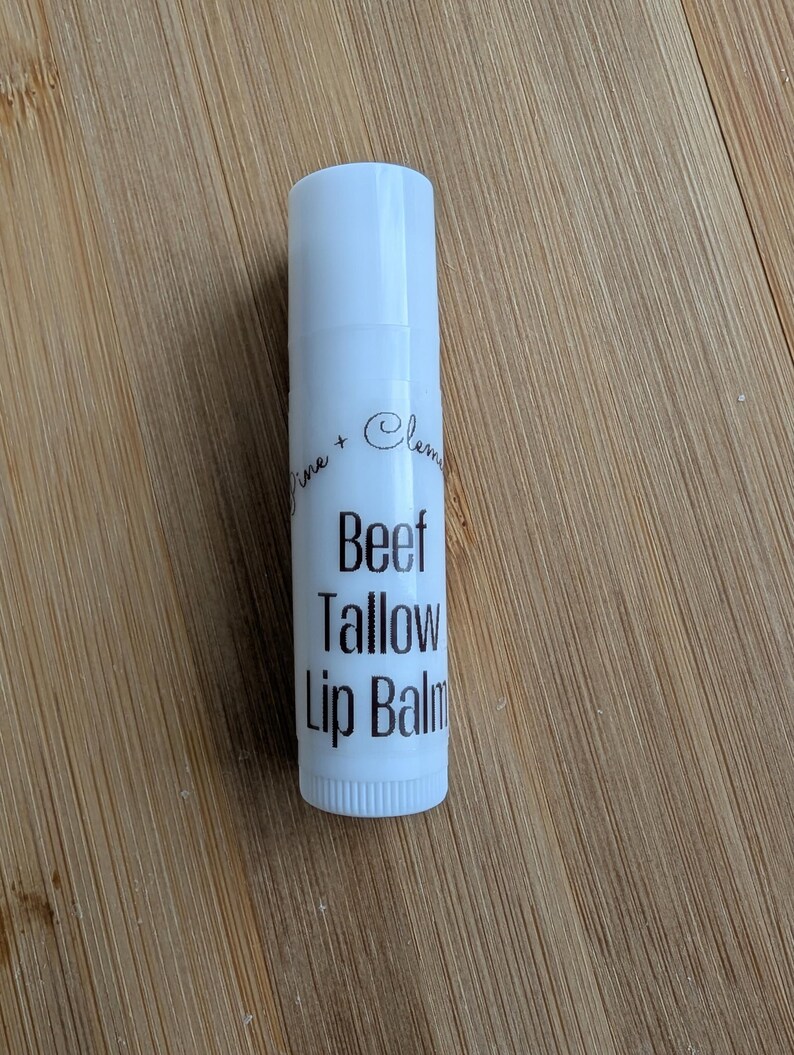 Puede incluir: Tubo blanco de b&aacute;lsamo labial con texto negro que dice "Lime + Clementine Beef Tallow Lip Balm".