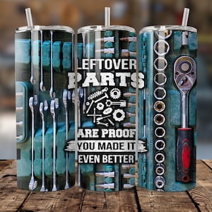 May include: Three stainless steel tumblers with a blue and silver design. The center tumbler has the text "Leftover Parts Are Proof You Made It Even Better".