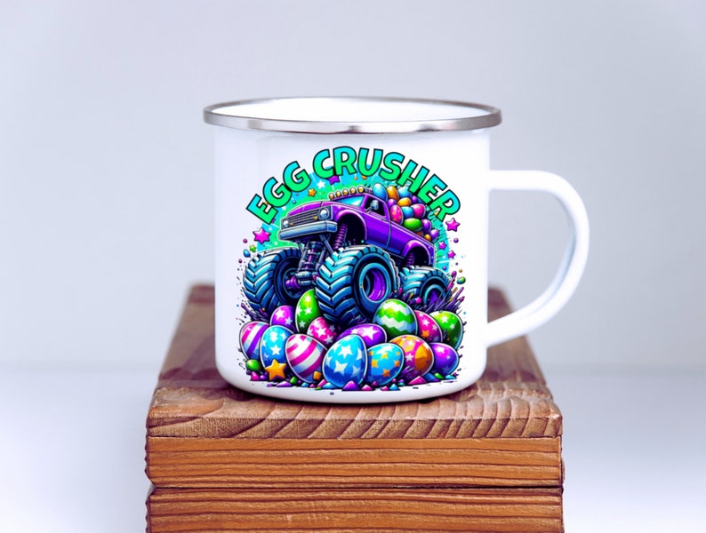 May include: White enamel mug featuring a purple monster truck carrying Easter eggs. The truck is driving over a pile of colourful Easter eggs. The text "Egg Crusher" is printed on the mug in green and white.