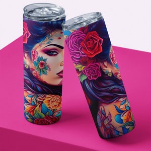 Pu&ograve; includere: Due bicchieri in acciaio inossidabile con un design colorato che presenta una donna con fiori e tatuaggi. Il design &egrave; vibrante e colorato con sfumature di rosa, blu, giallo e verde.