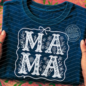 Puede incluir: Una camiseta azul oscuro con un dise&ntilde;o blanco que dice "MAMA" en una fuente decorativa con acentos florales.