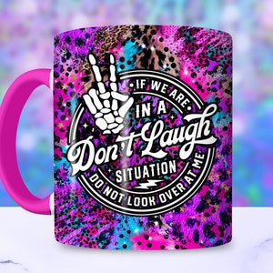 May include: A pink and purple coffee mug with a black and white graphic that says "If we are in a situation, don't laugh, do not look over at me". The graphic is surrounded by a circle with stars and a leopard print background.