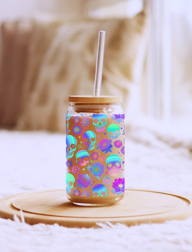May include: A glass drinking jar with a wooden lid and a clear drinking straw. The jar has a colourful pattern of skulls and flowers.