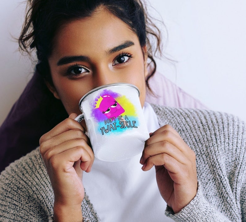 May include: A white enamel mug with a colorful graphic of a pink cartoon character with a crown and the text "Don't be a Twat-sicle".