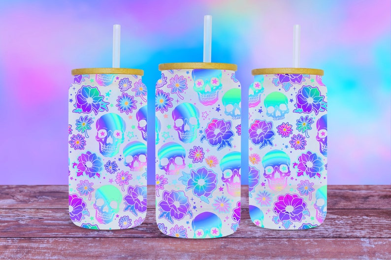 May include: Three white stainless steel tumblers with lids and straws. The tumblers are decorated with a holographic pattern of skulls and flowers in shades of pink, purple, and blue.