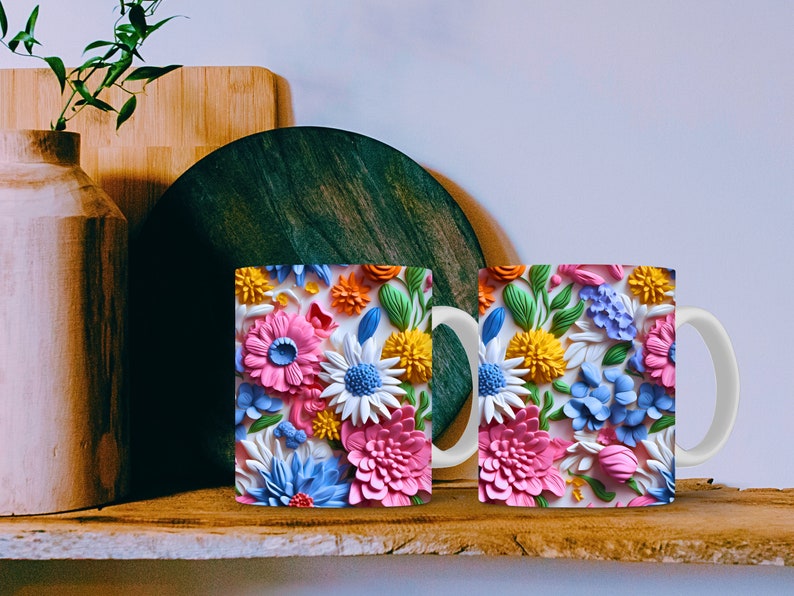 May include: Two white ceramic mugs with a colorful floral design. The flowers are pink, blue, yellow, and green. The mugs have a white handle.