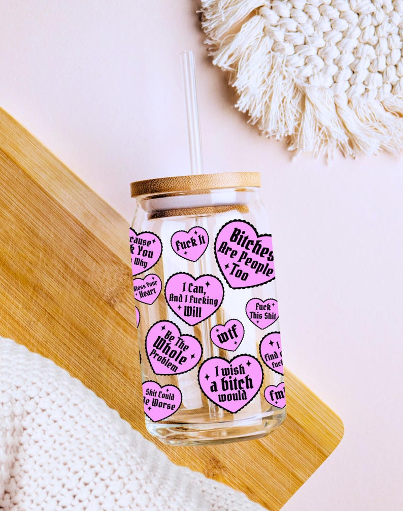 Puede incluir: Un vaso de vidrio transparente con tapa de bamb&uacute; y pajita transparente. El vaso est&aacute; decorado con pegatinas rosas en forma de coraz&oacute;n con varias frases en texto negro, incluyendo "Bitches Are People Too" y "I wish a bitch would".