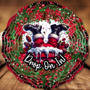 May include: A Christmas-themed wreath with a red and green color scheme. Santa Claus's legs are sticking out of a chimney, with the text "Drop On In!" below.