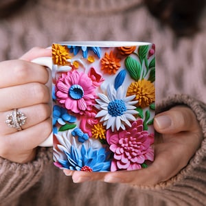 May include: A white ceramic mug with a colorful floral design. The flowers are pink, blue, yellow, and green and appear to be made of paper or fabric.