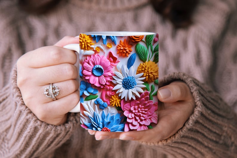 May include: A white ceramic mug with a colorful floral design. The flowers are pink, blue, yellow, and green and appear to be made of paper or fabric.