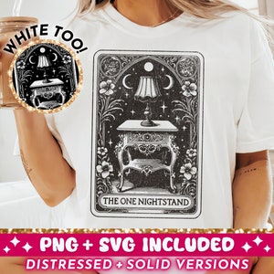 May include: White t-shirt with a black and white illustration of a nightstand with a lamp on top. The illustration is in the style of a tarot card and has the text "The One Nightstand" at the bottom. The text "White Too!" is written in gold glitter on the shirt.