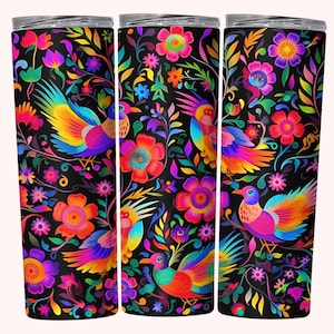 May include: A set of three insulated tumblers with a vibrant, colorful design. The black background is covered with bright flowers, leaves, and birds in shades of pink, orange, yellow, blue, and purple. The tumblers have a silver lid.
