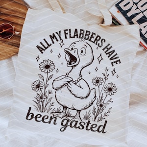 以下が含まれることがあります： 白いトートバッグに、白黒の鴨のイラストと「All my flabbers have been gasted」というテキストが描かれています。