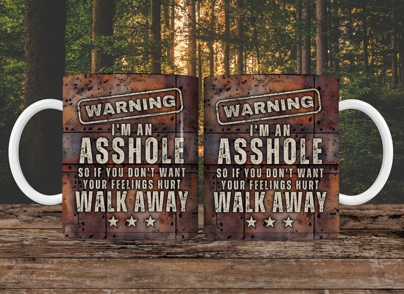 K&ouml;nnte beinhalten: Zwei wei&szlig;e Keramikbecher mit rustikalem braunem Hintergrund. Die Becher haben ein schwarzes Warnschild mit dem Text "WARNING I'M AN ASSHOLE SO IF YOU DON'T WANT YOUR FEELINGS HURT WALK AWAY" darauf gedruckt.