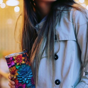 May include: A stainless steel tumbler with a colorful floral design. The flowers are in shades of blue, pink, red, yellow, and green. The tumbler has a black background.