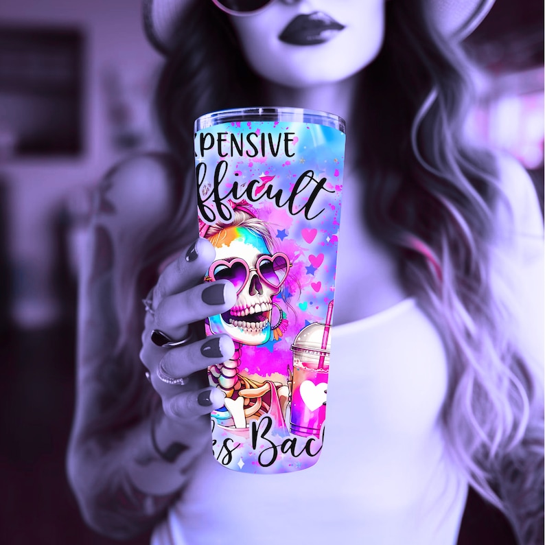 May include: A pink and blue tumbler with a skull wearing heart-shaped sunglasses and the text "Expensive, Difficult, Takes Back" on a white background.
