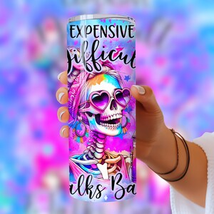 May include: A pink and purple stainless steel tumbler with a colorful skull design and the text "Expensive Difficult Looks Bad".