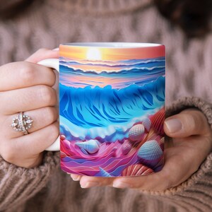 May include: A white ceramic mug with a colorful illustration of a seascape with a sunset, waves, and seashells. The mug is being held by a person's hands.
