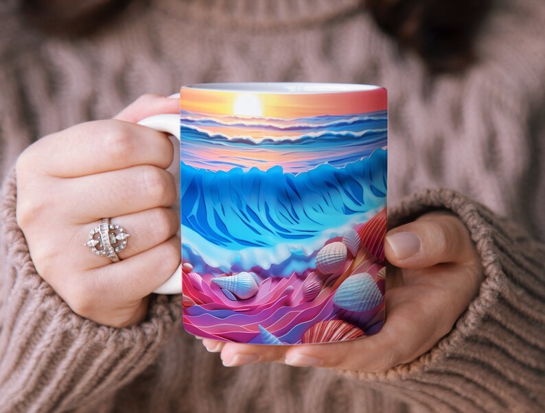 May include: A white ceramic mug with a colorful illustration of a seascape with a sunset, waves, and seashells. The mug is being held by a person's hands.