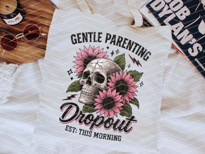 K&ouml;nnte beinhalten: Wei&szlig;e Einkaufstasche mit einem Totenkopf- und Blumenmotiv. Der Text lautet "Gentle Parenting Dropout Est: This Morning".
