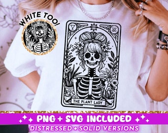 May include: A white t-shirt with a black and white illustration of a skeleton woman with flowers in her hair. The illustration is in the style of a tarot card and says "The Plant Lady". The text "White Too!" is in a circle above the illustration.