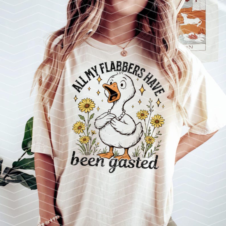 以下が含まれることがあります： 漫画の鴨と花が描かれた白いTシャツ。シャツのテキストは「All my flabbers have been gasted」です。