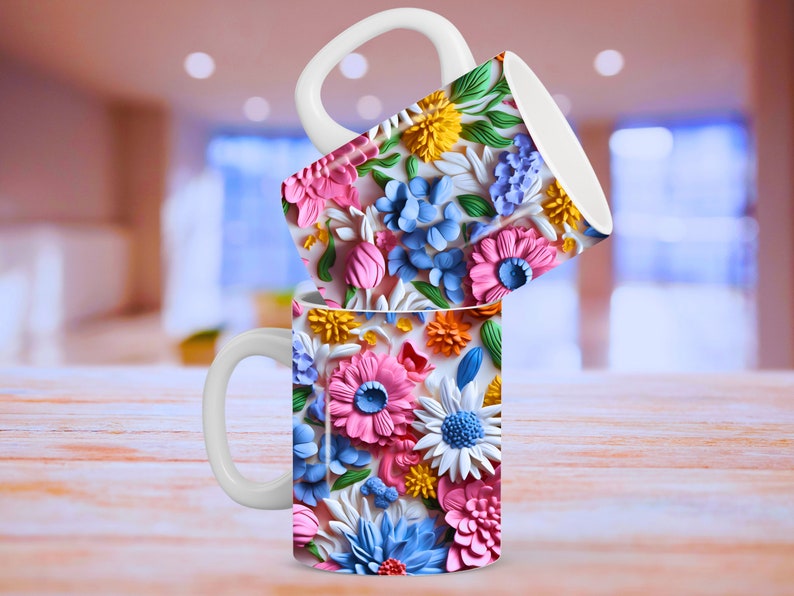 May include: Two white ceramic mugs with a floral design. The mugs feature a colorful pattern of pink, blue, white, and yellow flowers. The mugs are stacked on top of each other.