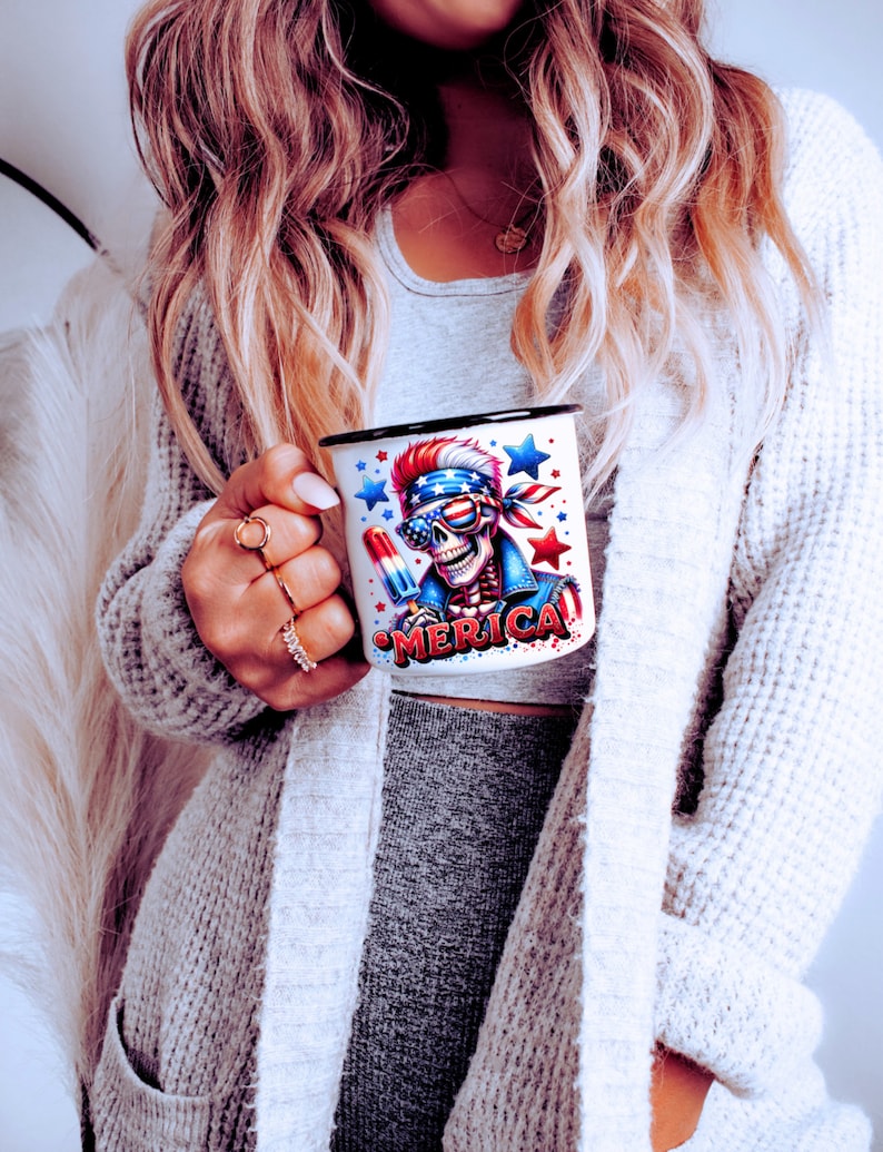 May include: White ceramic mug with a black rim and handle. The mug features a colorful graphic of a skeleton wearing a bandana and sunglasses, holding a popsicle. The text "MERICA" is printed on the mug.