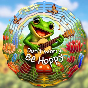 May include: A green frog playing a guitar with the words "Don't Worry Be Hoppy" on a mushroom. The frog is surrounded by flowers and butterflies.